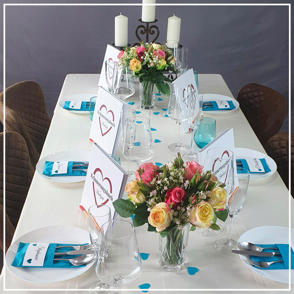 edel gedeckter Hochzeitstisch mit aufgestellten Gastgeschenkbüchern und zwei schönen Rosensträußen